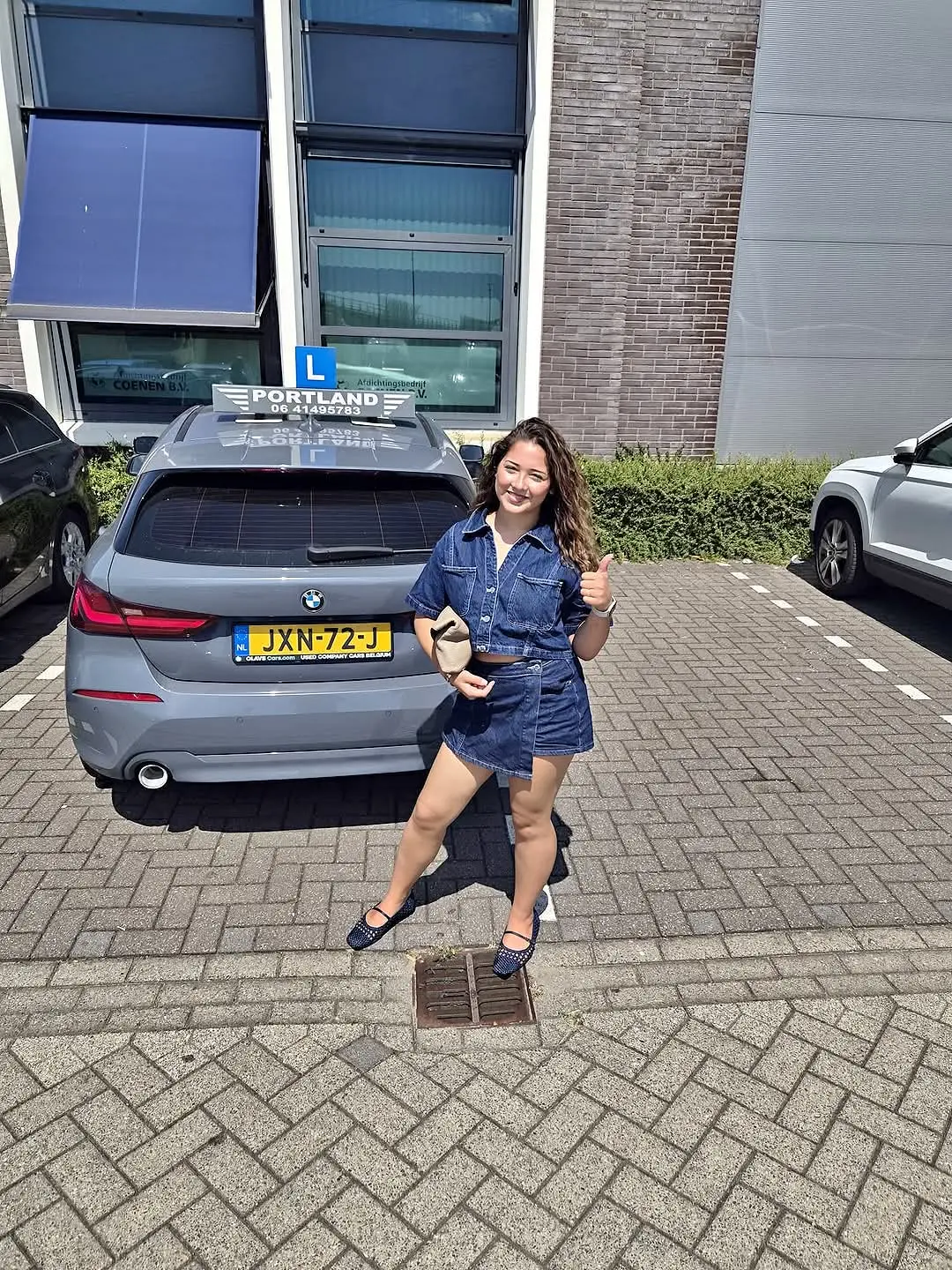 Geslaagde leerling geeft duim omhoog bij lesauto
