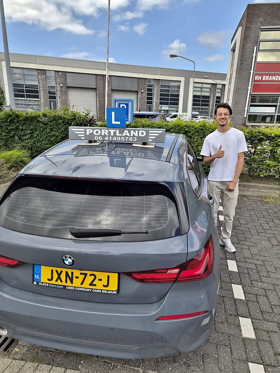 Een leerling geeft een duim omhoog bij een lesauto