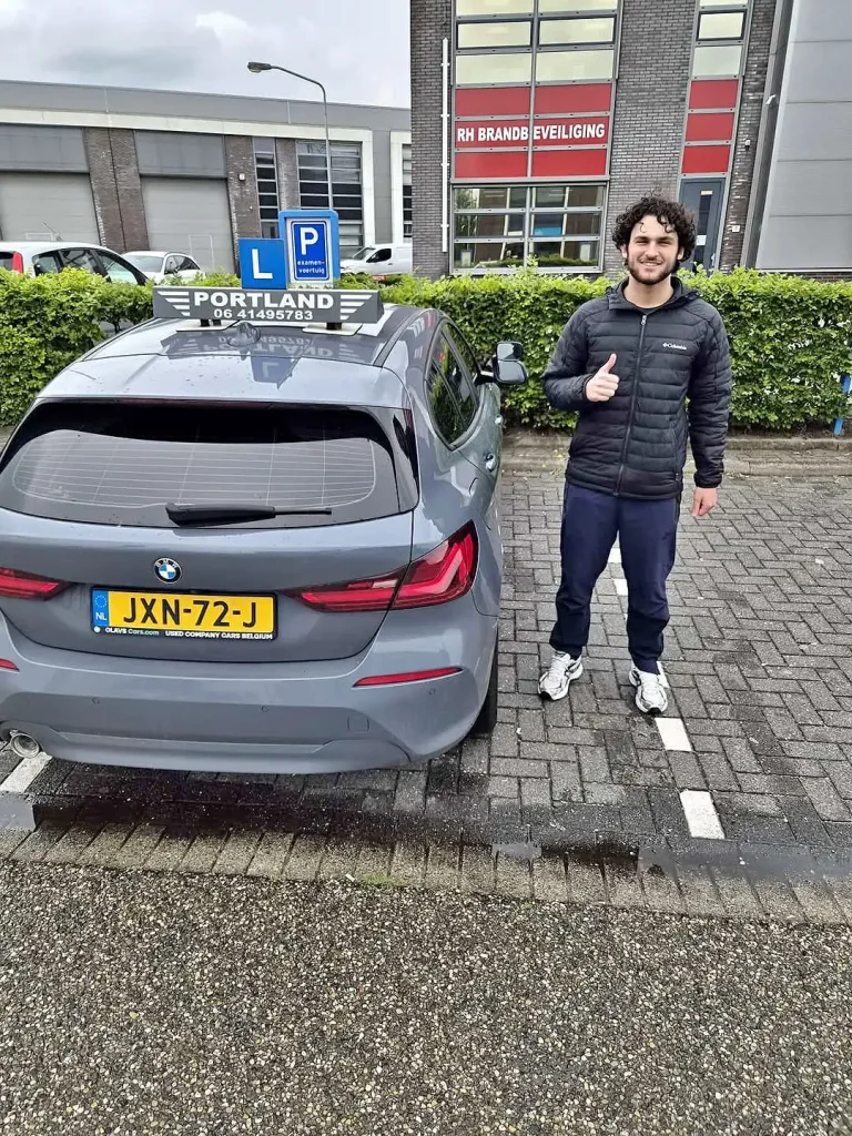 ec10dd27-d70c-4190-9fac-2a15f421aa67 Een trotse leerling geeft een duim omhoog naast de lesauto van rijschool Portland