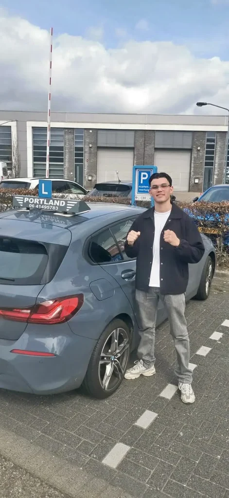 edc3b6be-4ef8-4ea7-8753-8cc14595156f Geslaagde leerling staat trots bij een lesauto van rijschool Portland